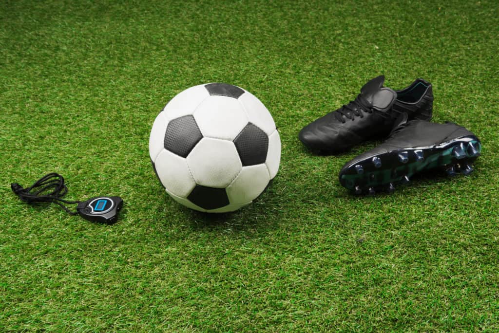fodbold og fodboldstoevler paa groent graes 1024x684